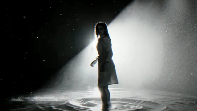 She stands in a beam of light in flooded water, from Prey For Me